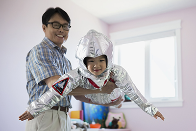 Portrait of grandfather flying granddaughter in astronaut costume