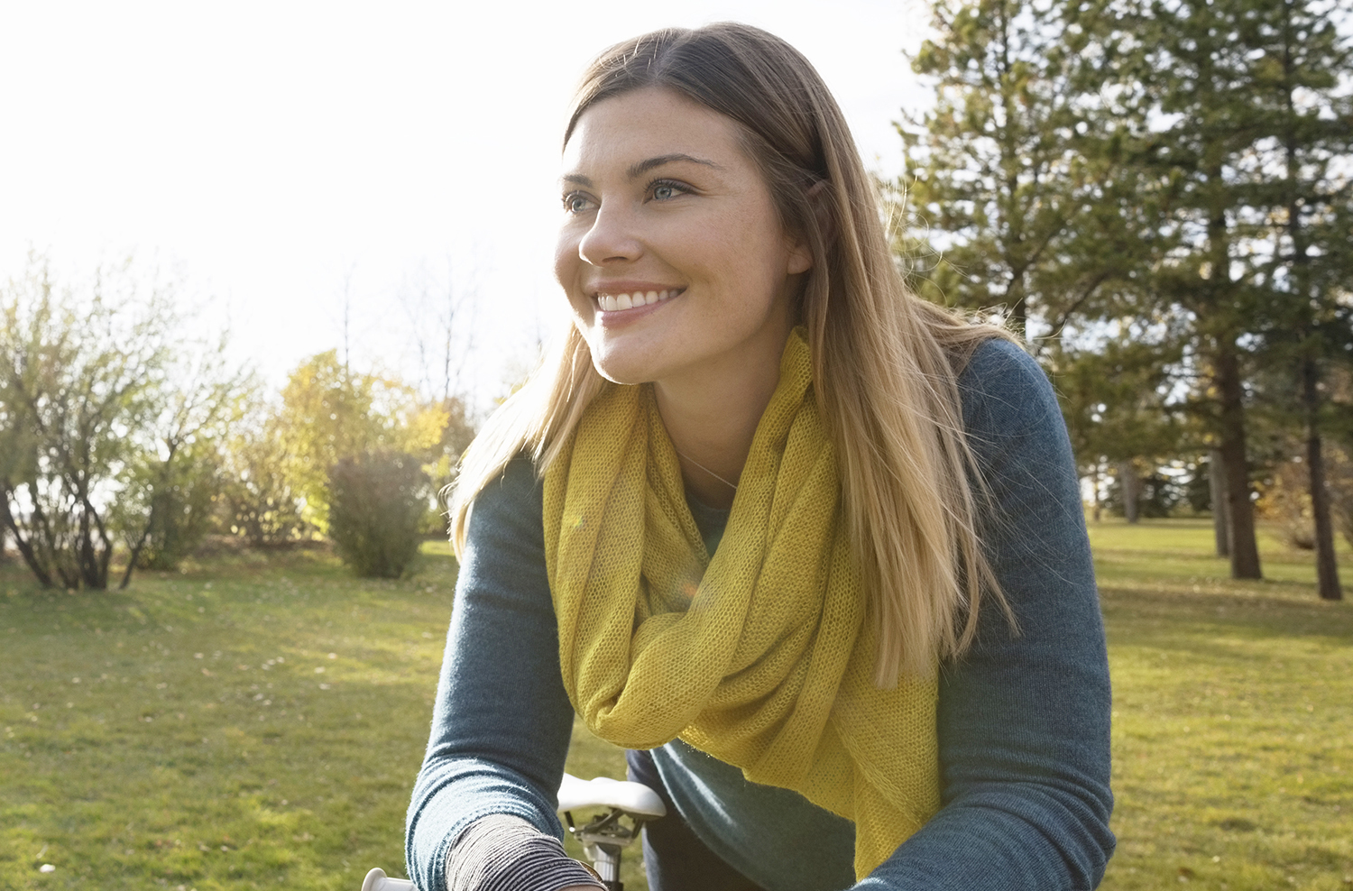 Smiling woman with bicycle looking away in sunny park