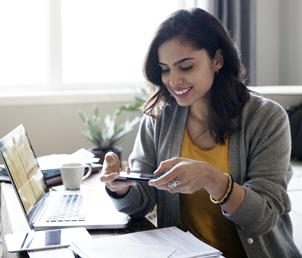 Young woman depositing check online with camera phone in living room