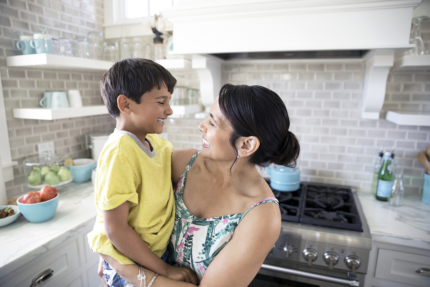 Smiling mother holding son in kitchen