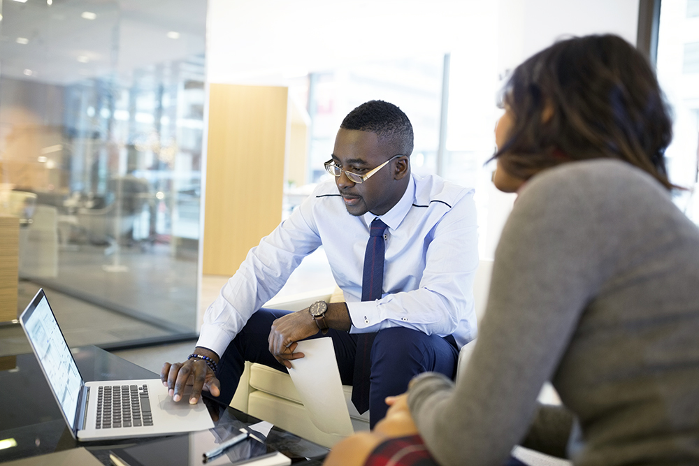 Business people working at laptop in office lobby