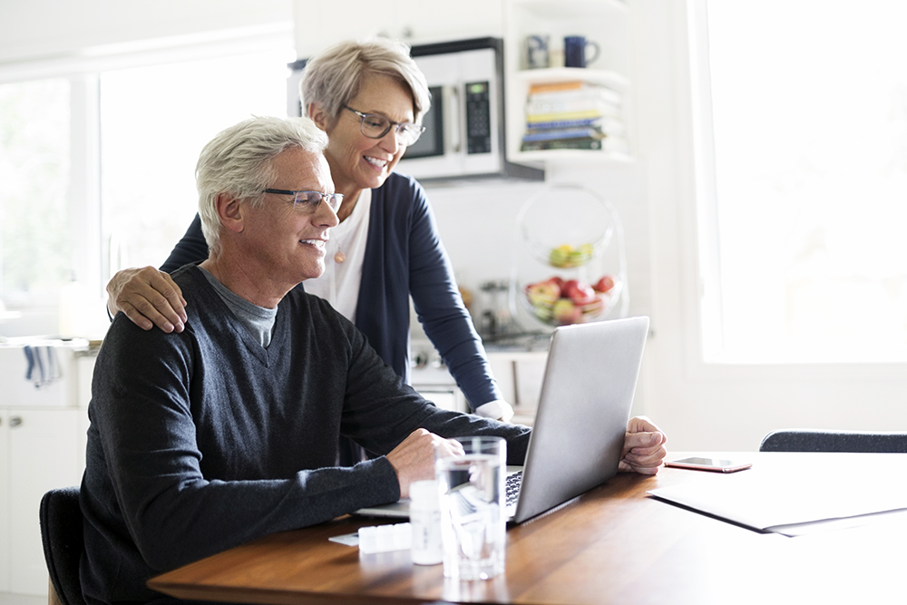 Senior couple using laptop at kitchen table