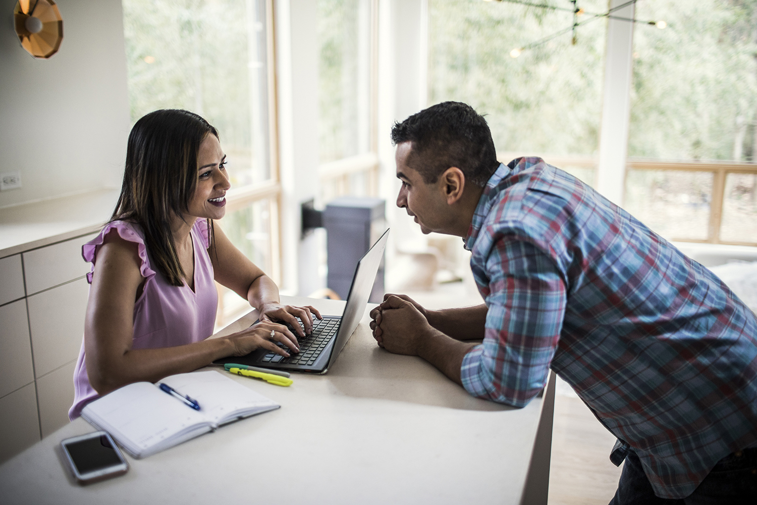 Husband and wife using laptop in kitchen