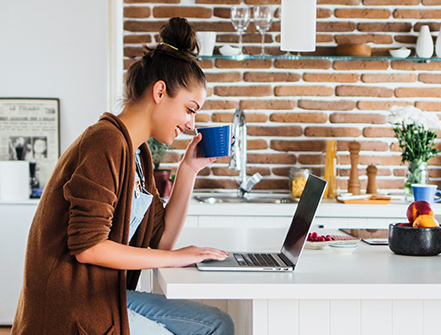 Caucasian woman using laptop in kitchen.