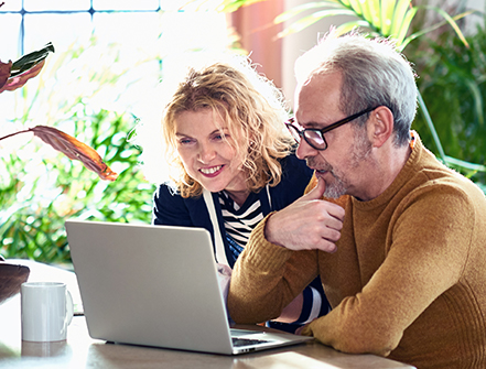 Mature couple in their 50s using computer at home.