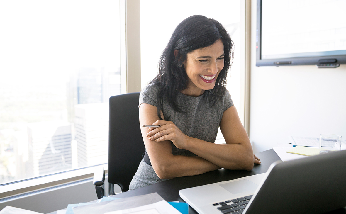 Smiling woman video conferencing at laptop in conference room