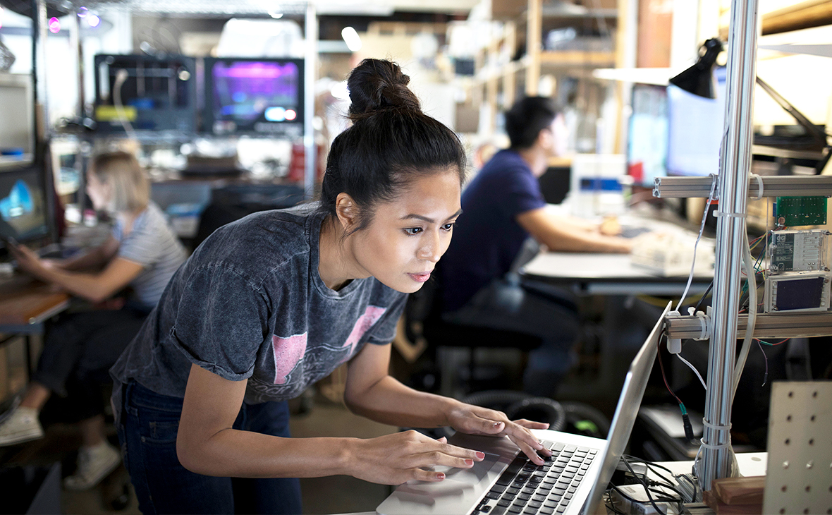 Focused female engineer working at laptop in workshop.