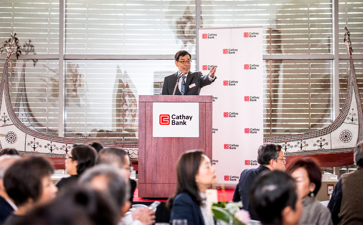 Cathay Bank executive presents behind a podium at the 2018 Economic Outlook Seminar event at Bowers Museum in California.
