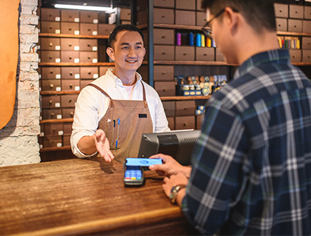 Un comerciante guía a su cliente para que use el método de pago electrónico en su tienda.