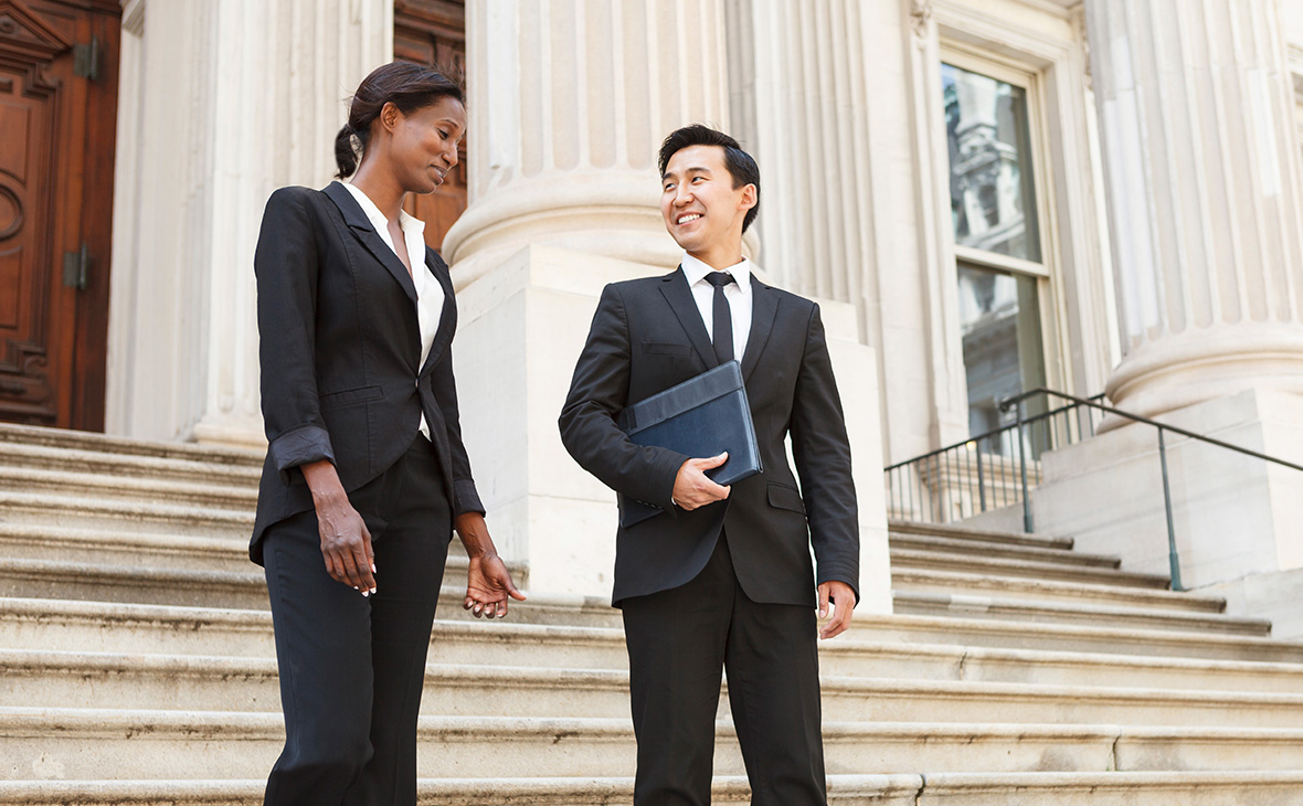 A well dressed man and woman smiling as they as they walk down steps of a courthouse building. 
