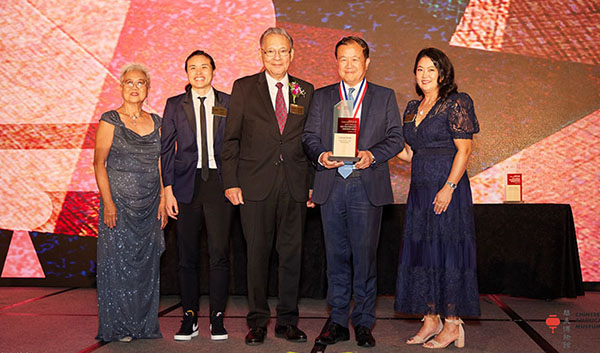 A group of people stand on a stage as special guests and honorees for the Chinese American Museum’s Historymakers Gala.