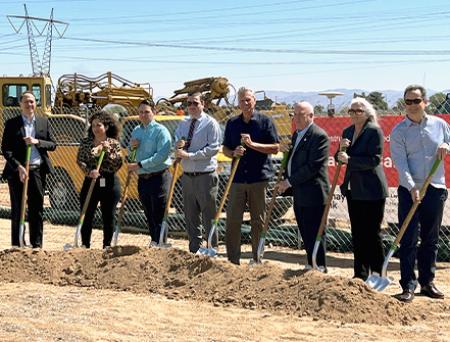 Staff from Cathay Bank and from the Federal Home Loan Bank stand on a gravel pit with shovels with other community professionals in suits.
