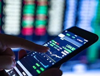 A person holds their cellphone and taps on the screen showing their investment options on a finance app.