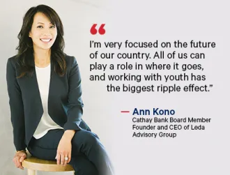 Executive businesswoman in a blue suit and white blouse, Ann Kono, smiles and poses in a professional studio setting for a corporate headshot.