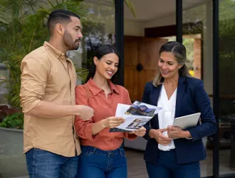 A professional female real estate banker shares purchase options to a female and male couple interested in buying a home while standing in a patio.