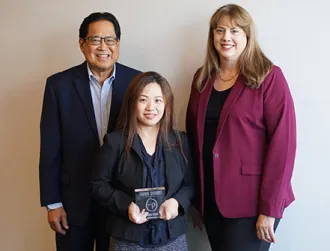 Three executive employees pose with an award from Personify Health in a conference room with a Cathay Bank logo displayed.