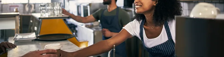Young woman serving a customer in her coffee shop
