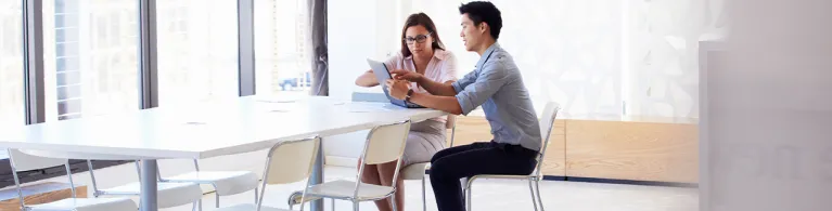 Two people working on a tablet in a meeting room