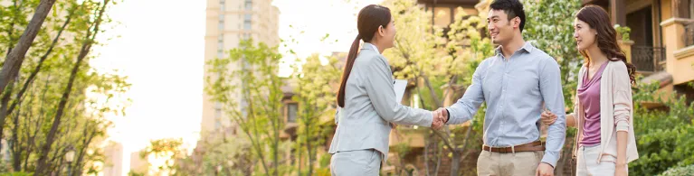 Happy young couple shaking hands with realtor