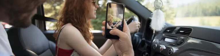 Boyfriend videotaping girlfriend driving car, enjoying road trip