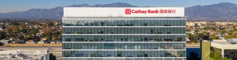 The Cathay Bank headquarters building stands in front of the San Gabriel Mountain range in California.