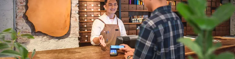 A merchant guides his client to use electronic payment method at his place of business.