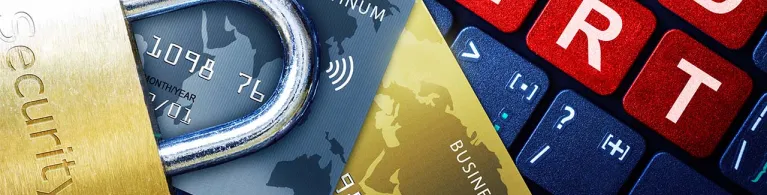 A computer keyboard displays the phrase "Fraud Alert" in red, white, and blue, with two credit cards and a security lock on top to imply awareness of scammers.