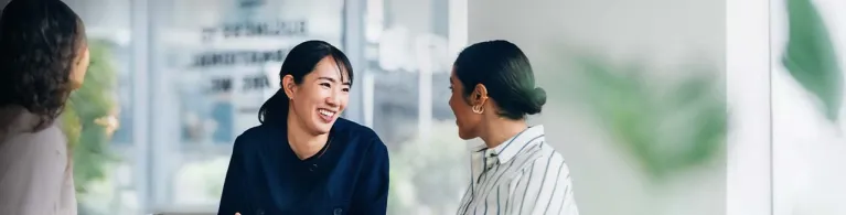 Two professional women sit at a conference table while reviewing financial literacy documents.