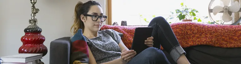 Woman using digital tablet on sofa