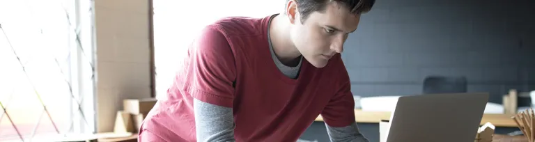 Focused male designer working at laptop in workshop