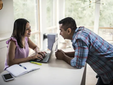 Husband and wife using laptop in kitchen