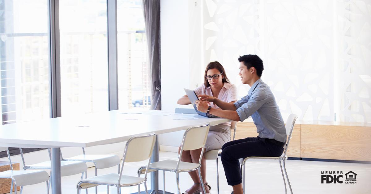 Two people working on a tablet in a meeting room