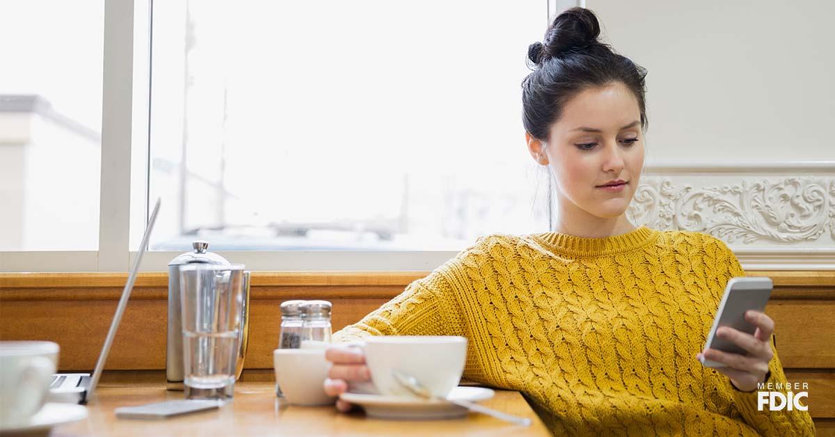 Woman texting and drinking cappuccino in cafe