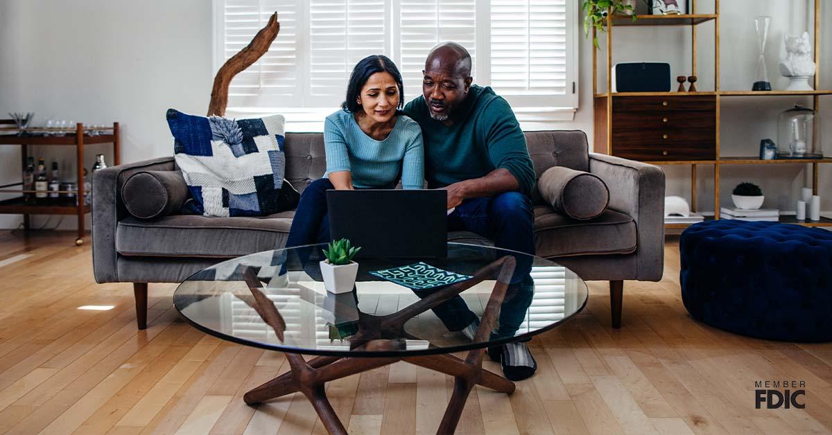 Mature married couple at home on the sofa looking at laptop