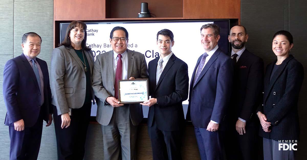 Los miembros del equipo de Cathay Bank posan con el Premio Gallagher y los miembros de la firma en una sala de conferencias.