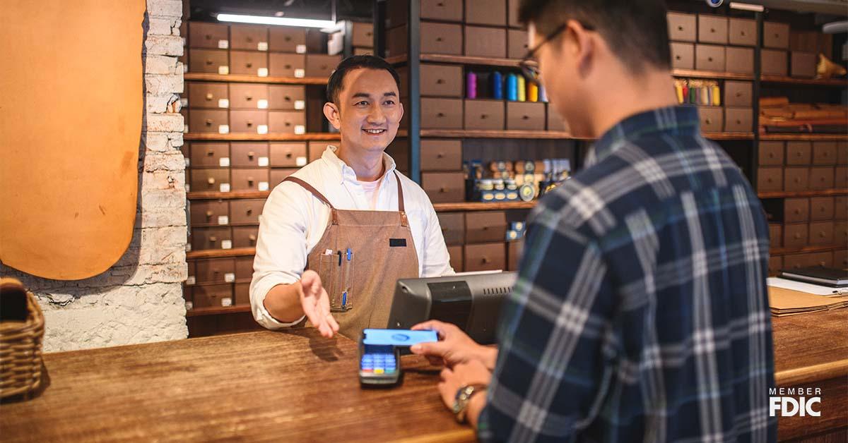 Un comerciante guía a su cliente para que use el método de pago electrónico en su tienda.