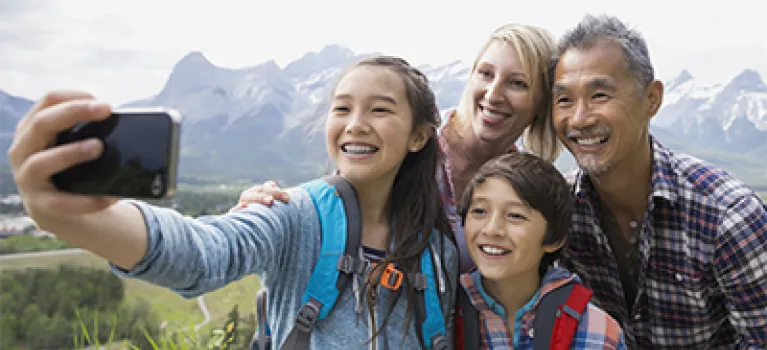 Family taking cell phone picture on rural hillside