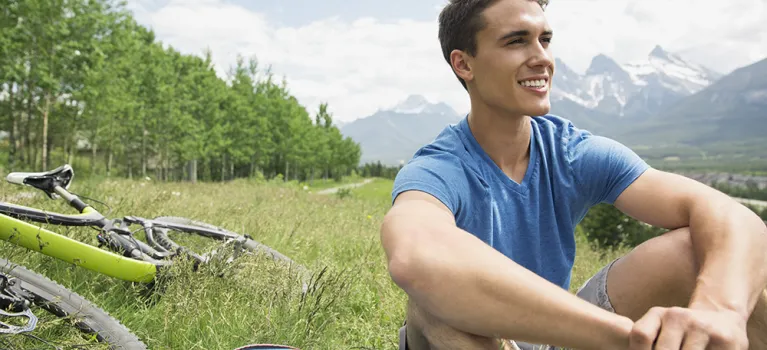 Man with mountain bike sitting in grass