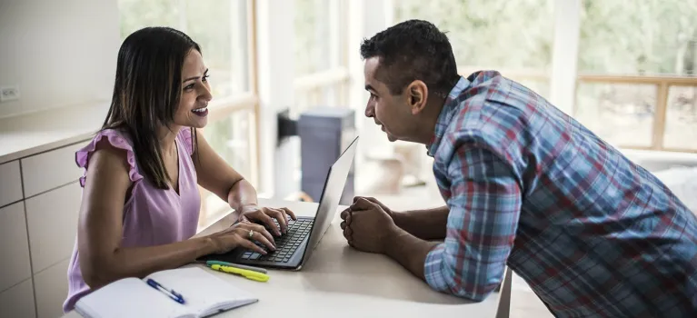 Husband and wife using laptop in kitchen