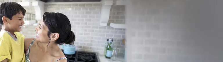 Smiling mother holding son in kitchen