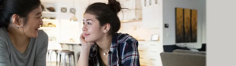 Mother and teenage daughter holding hands drinking tea.