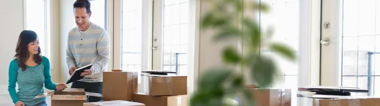 Couple unpacking cardboard boxes in new home