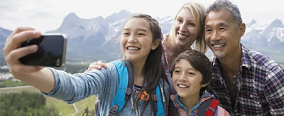 Family taking cell phone picture on rural hillside