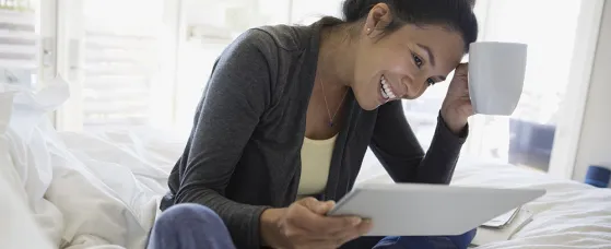 Smiling woman using digital tablet on bed