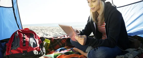 Woman using digital tablet in tent on beach