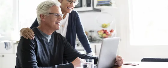 Senior couple using laptop at kitchen table