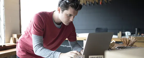 Focused male designer working at laptop in workshop