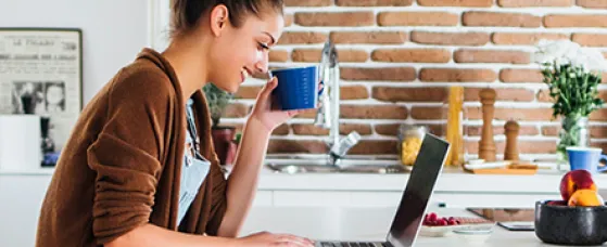 Caucasian woman using laptop in kitchen.