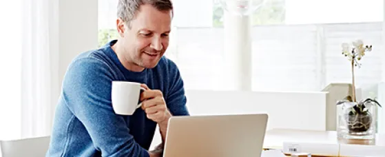 Man working at home using laptop drinking coffee