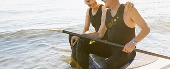 Senior couple on paddle board in ocean.